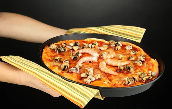 Mãos segurando pizza com frutos do mar no fundo cinza — Fotografia de Stock