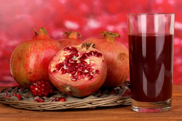 Reife Granatäpfel auf Weidenwippe mit Glas Granatapfelsaft auf Holztisch auf Herbsthintergrund — Stockfoto