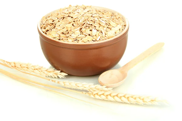 Brown bowl full of oat flakes with spikelets and wooden spoon isolated on white — Stock Photo, Image