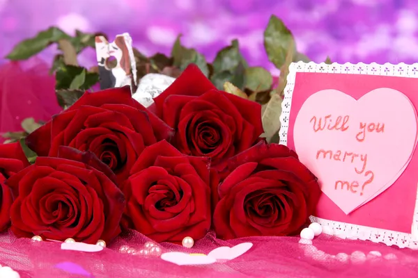 Красивый букет роз с валентином на розовой ткани на фиолетовом фоне крупным планом — стоковое фото