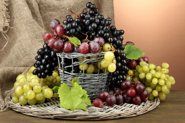 Assortiment van rijp zoete druiven in mand, op bruine achtergrond — Stockfoto