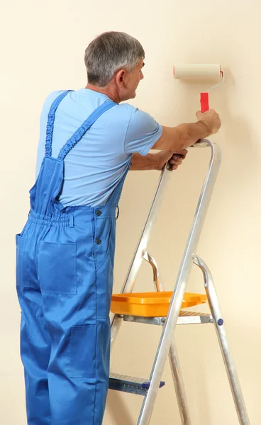 Pintor masculino pinta la pared en la habitación de cerca —  Fotos de Stock