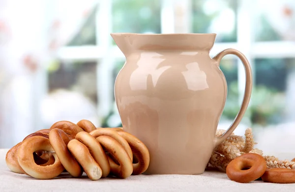 Jar of milk, tasty bagels and spikelets on table — Stock Photo, Image