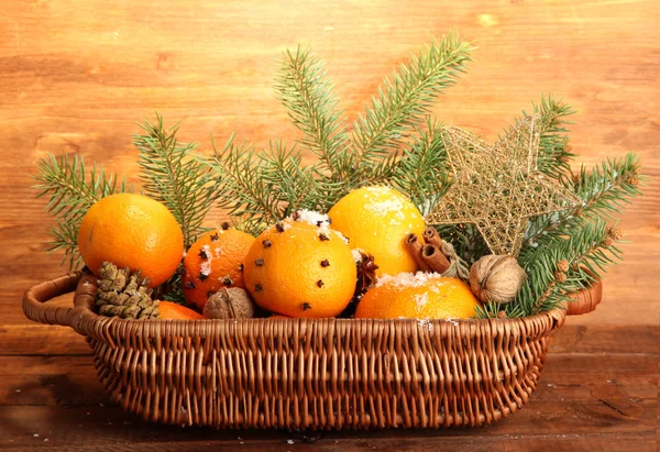 Composição de natal em cesta com laranjas e abeto, sobre fundo de madeira — Fotografia de Stock