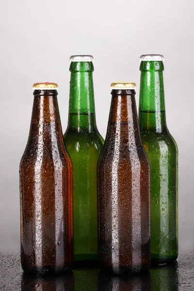 Gri arka plan üzerinde renkli cam bira şişeleri — Stok fotoğraf