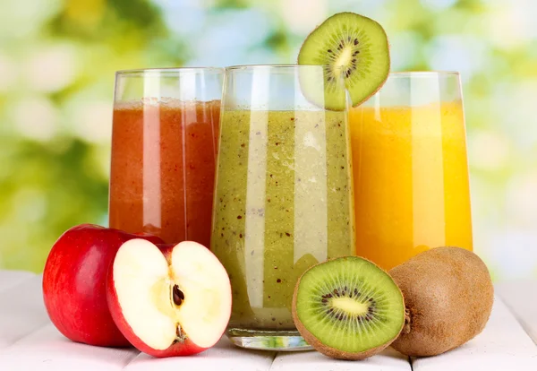 Jus buah segar di meja kayu, di latar belakang hijau — Stok Gambar Jus buah segar di meja kayu, di latar belakang hijau Stok Lukisan