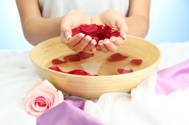 kadın eliyle su yaprakları, mavi zemin üzerine ahşap kase