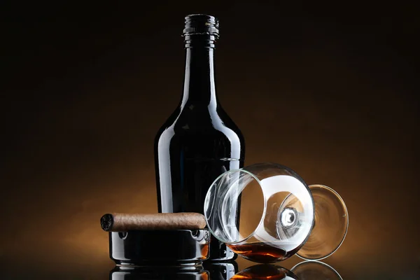 Şişe ve bardak brendi ve puro kahverengi zemin üzerinde — Stok fotoğraf