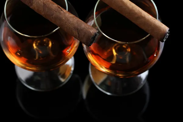 Dvě sklenky brandy a doutníků na černém pozadí — Stock fotografie