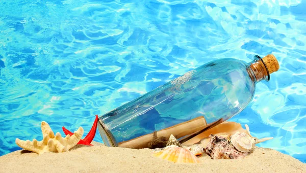 Glasflasche mit Hinweis innen auf Sand, auf blauem Meeresgrund — Stockfoto