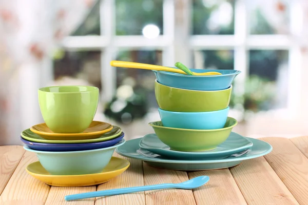 Colorful tableware on wooden table on window background — Stock Photo, Image