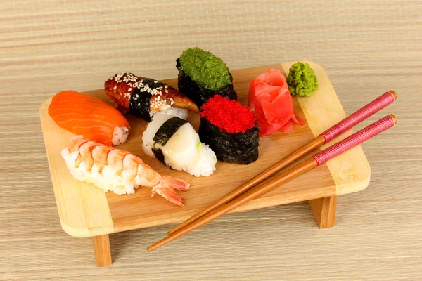 Délicieux sushi servi sur planche de bois sur tapis de bambou — Photo