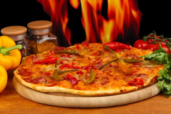 Tasty pepperoni pizza with vegetables on wooden board on flame background — Stock Photo, Image