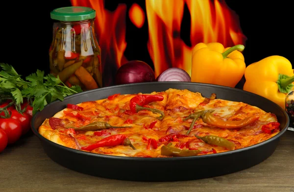 Смачна піца пепероні в сковороді з овочами на фоні полум'я — стокове фото