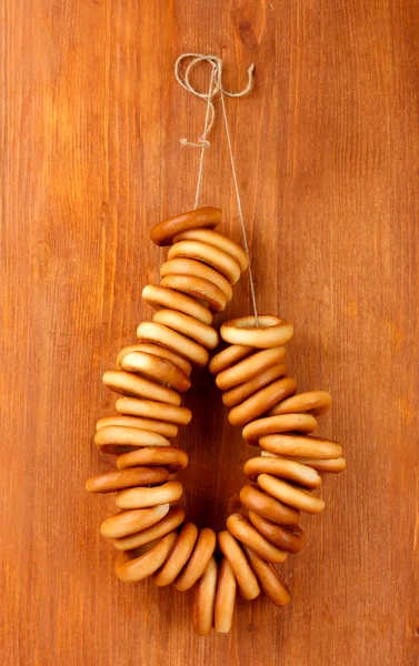Tasty bagels on rope, on wooden background — Stock Photo, Image