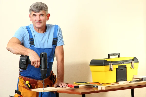 Builder drills board on table on wall background — Stock Photo, Image