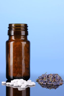 şişe hap ve otlar üzerinde mavi arka plan ile. homeopati kavramı