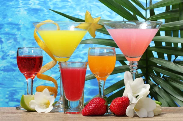 Exotische cocktails en bloemen op tafel op blauwe zee achtergrond — Stockfoto