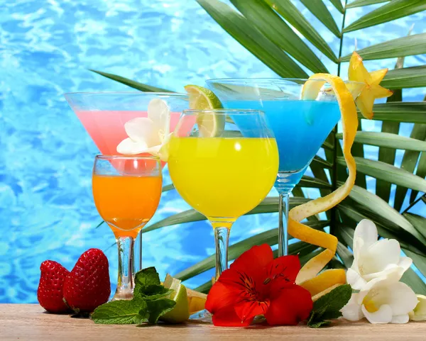 Екзотичні коктейлі та квіти на столі на синьому морському фоні — стокове фото