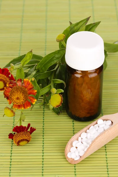 Flacon de médicaments avec comprimés et fleurs sur tapis de bambou — Photo