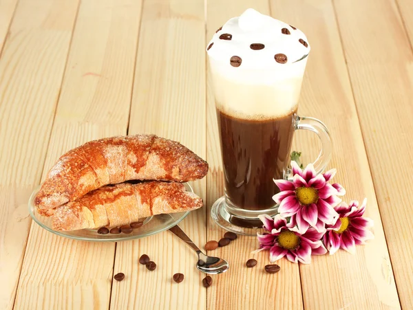 Стакан свежего кофе и блюдце с бубликами на деревянном фоне — стоковое фото