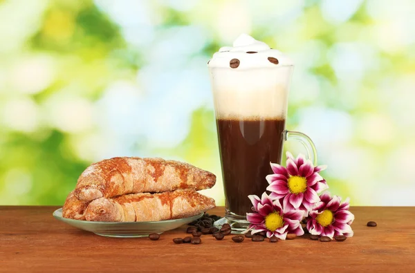 Bicchiere di caffè fresco cocktail e piattino con bagel su sfondo verde brillante — Foto Stock