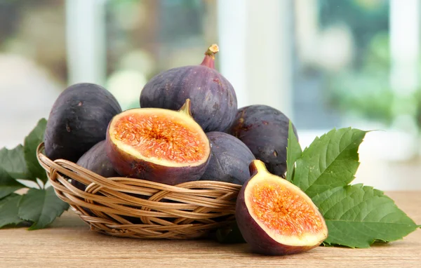 Mogen söt fikon med blad i korg, på träbord, på fönsterbakgrund — Stockfoto