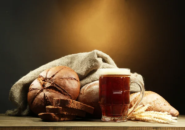 Tankard svagdricka och råg bröd med öron, på träbord på brun bakgrund — Stockfoto