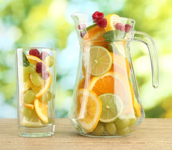 Burk och glas med citrusfrukter och hallon på grön bakgrund — Stockfoto
