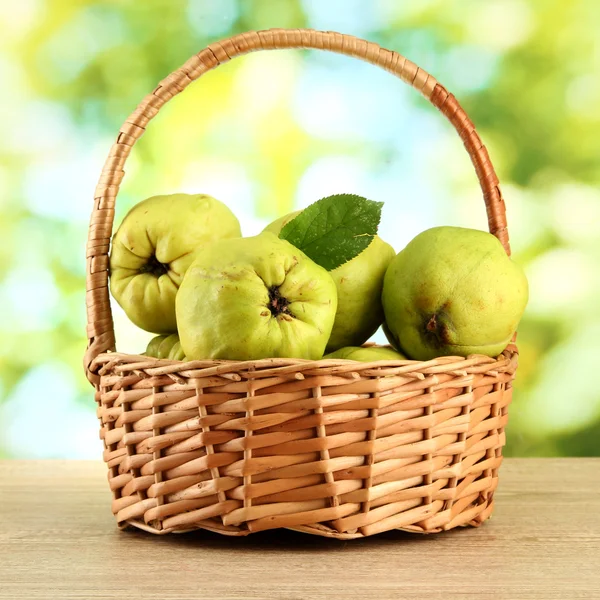 Mele cotogne dolci con foglie in cesto, su sfondo verde — Foto Stock