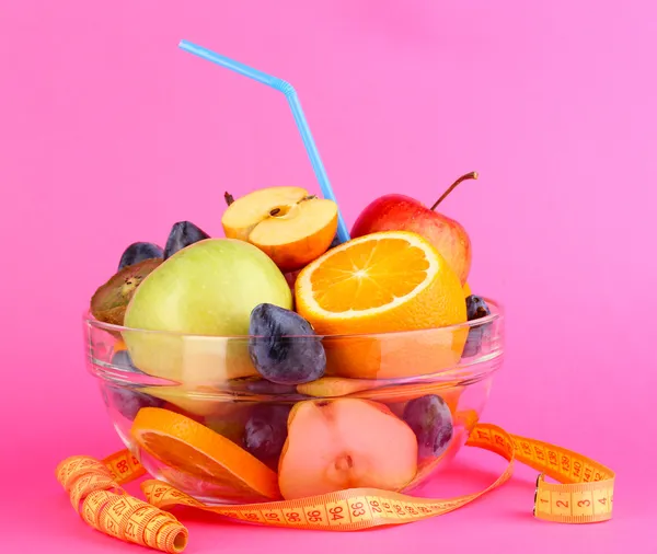 玻璃碗水果饮食和测量上粉红色背景的磁带 — 图库照片