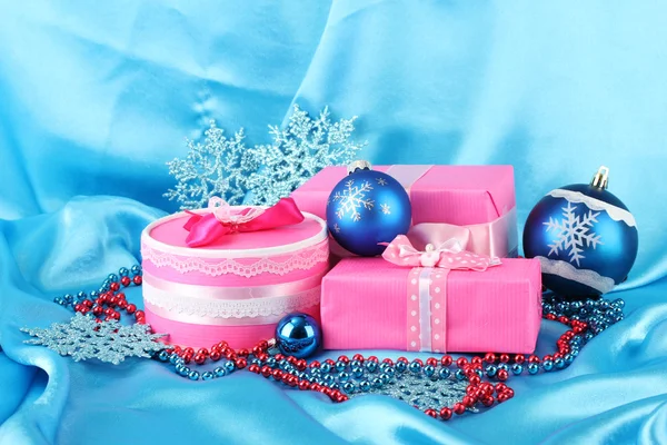 Hermosos regalos rosados con bolas azules de Navidad, copos de nieve y perlas sobre fondo azul —  Fotos de Stock