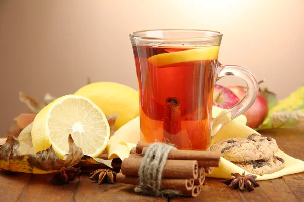 Tazza di tè caldo e foglie autunnali, su sfondo marrone — Foto Stock