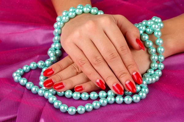 Female hands holding beads on color background — Stock Photo, Image