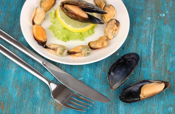 Snack of mussels and lemon on plate on blue wooden table — Stock Photo, Image