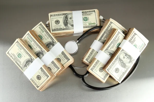 Healthcare cost concept: stethoscope and dollars on gray background — Stock Photo, Image