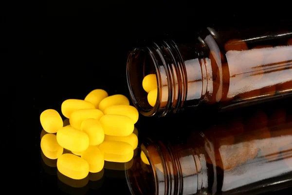 Pills in bottle isolated on black — Stock Photo, Image