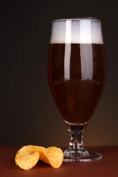 Glas öl med chips på brun bakgrund — Stockfoto