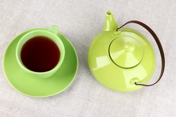 Top view of cup of tea and teapot on tablecloths — Stock Photo, Image