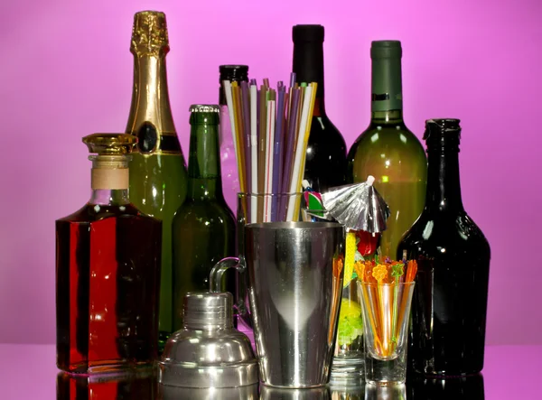 Збір напоїв, коктейльний шейкер та інше обладнання бармена на кольоровому фоні — стокове фото