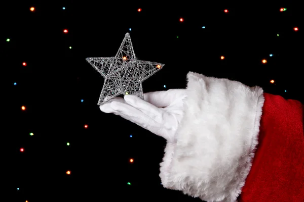 Santa Claus mano celebración de la estrella de Navidad sobre fondo brillante — Foto de Stock