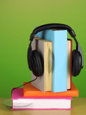 yeşil zemin üzerine ahşap masa kitap üzerinde kulaklık