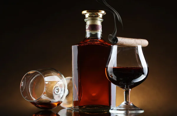 Bottiglia e bicchieri di brandy e sigaro su sfondo marrone — Foto Stock