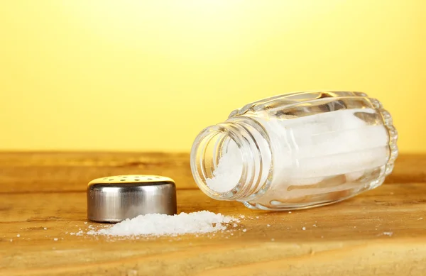 Salt mill, on wooden table on yellow background — Stock Photo, Image