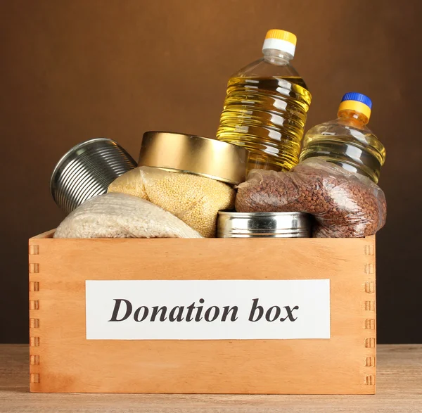 Scatola di donazione con cibo su sfondo marrone primo piano — Foto Stock
