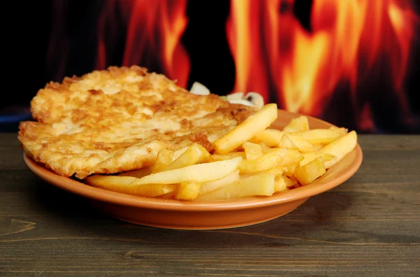 Stekt kyckling kotlett med pommes frites, på brand bakgrund — Stockfoto