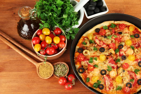 Composición colorida de deliciosa pizza, verduras y especias sobre fondo de madera de cerca —  Fotos de Stock