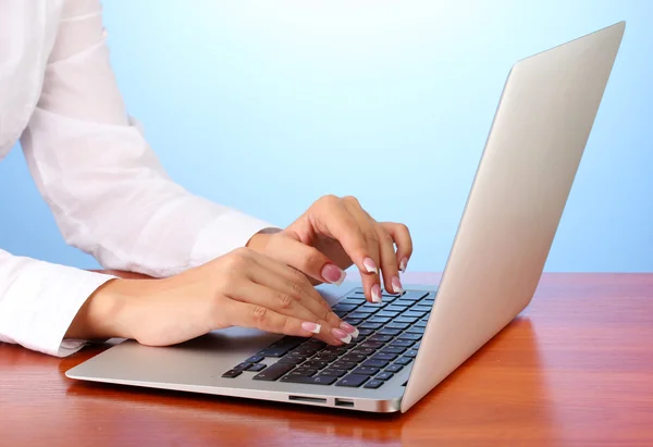 Mani di donna d'affari digitando sul computer portatile, su sfondo blu primo piano — Foto Stock