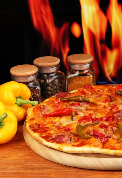 Смачна піца пепероні з овочами на дерев'яній дошці на фоні полум'я — стокове фото