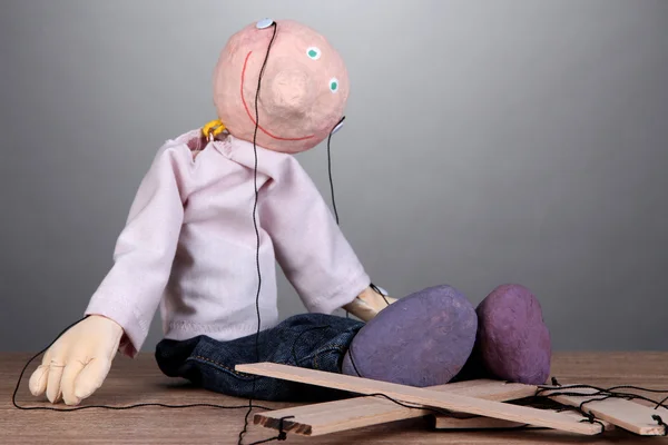 Деревянная кукла сидит на сером фоне — стоковое фото